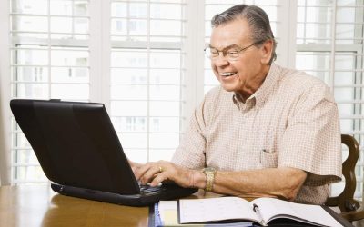 Mature Caucasian man typing on laptop in home.